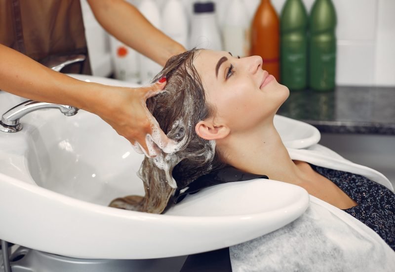 Woman washing head in a hairsalon Hairdresser washing head her client. Woman in a hair salon
